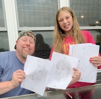a man and a woman holding up drawings of a horse